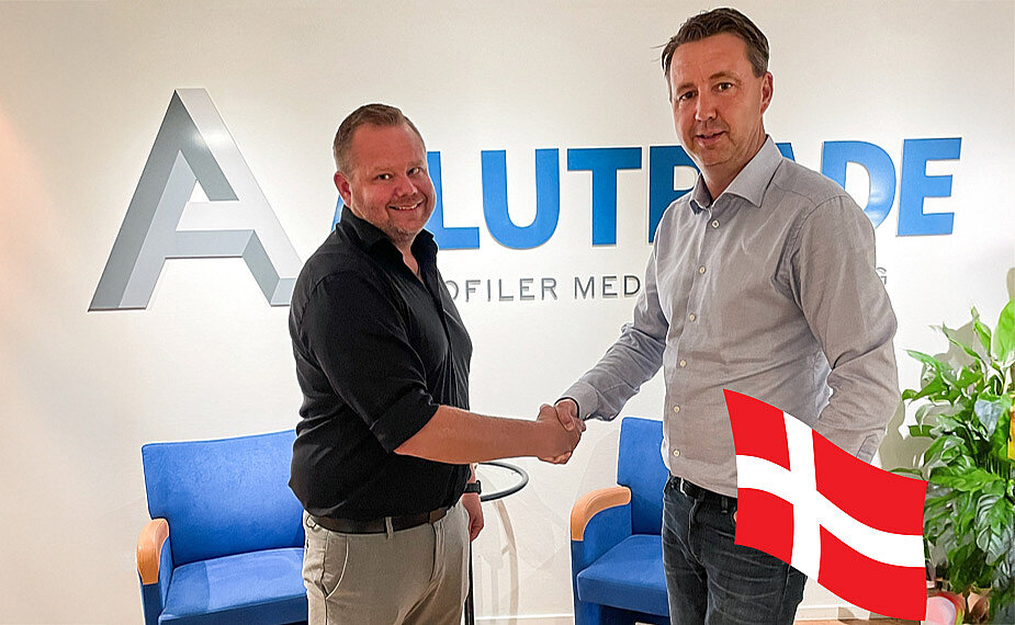 Alutrades VD och v&aring;r nya exports&auml;ljare skakar hand framf&ouml;r f&ouml;retagets logotyp.